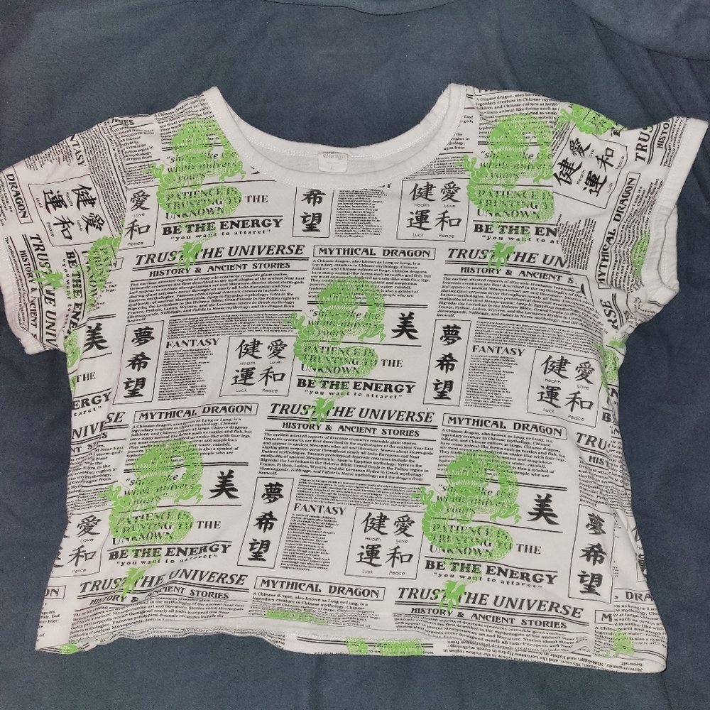 Angel Energy cropped newspaper print shirt with green dragons on it